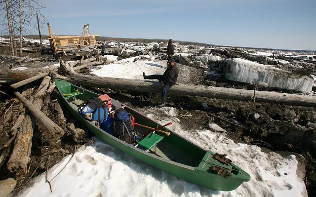 Sam Nathaniel climbs over a log following his neighbor Gary Bessette as they climb over blocks of Yukon River ice Monday, May 20, 2013, at Circle. An ice jam Sunday morning caused the river to rise rapidly flooding the village 160 miles northwest of Fairbanks. (AP Photo/ Fairbanks Daily News-Miner, Sam Harrel)