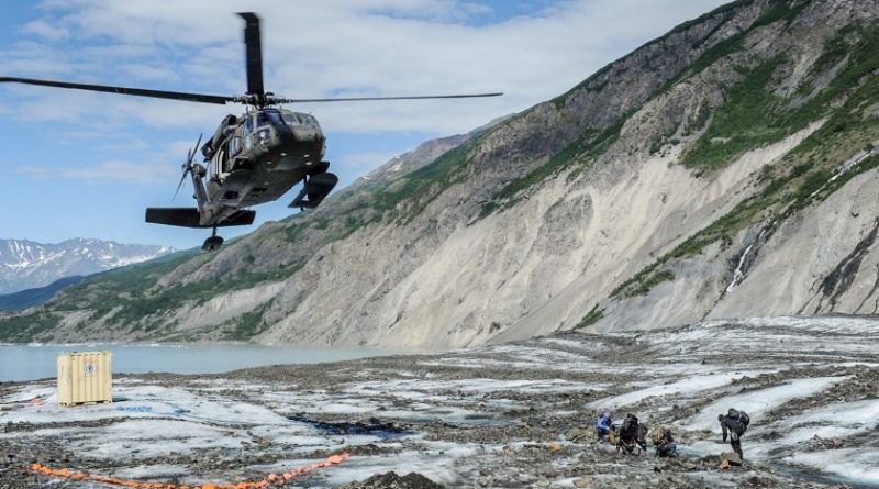 Members of a specialized investigative team from the Join POW/MIA Accounting Command wait as a UH - 60 Blackhawk from Joint Base Elmendorf-Richardson comes in for a landing to transport them back after a day of assessing a historic aircraft crash site. The mission of the Joint POW/MIA Accounting command is to conduct global search, recovey and laboratory operations to identify unaccounted-for Americans from past conflicts in order to support hte Department of Defense's personnel accounting efforts. (Clifford Bailey / US Navy)