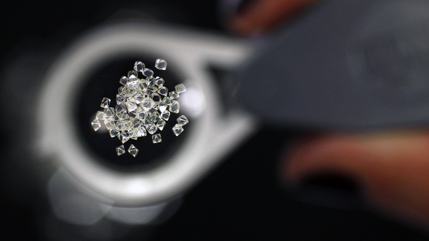 Uncut diamonds from southern Africa and Canada are seen through a jeweller's loupe at De Beers headquarters in London