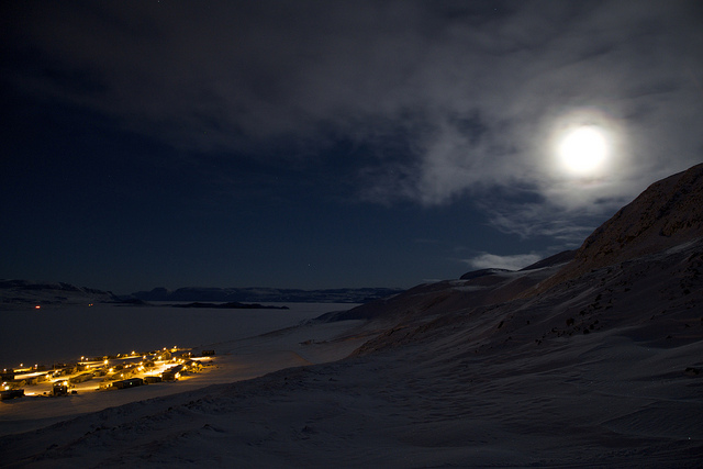 Part of Arctic Bay glows beneath the hills surrounding the community under the almost full moon.(Clare Kines)