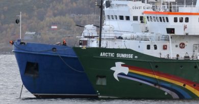 A crew member keeps watch aboard a Russian coast guard boat, left, as the Greenpeace ship 'Arctic Sunrise', right, is anchored next to it, in a small bay near Severomorsk, Russia. (The Associated Press)