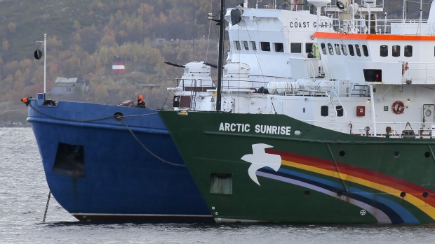 A crew member keeps watch aboard a Russian coast guard boat, left, as the Greenpeace ship 'Arctic Sunrise', right, is anchored next to it, in a small bay near Severomorsk, Russia. (The Associated Press)