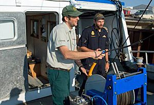 Parks Canada underwater archeologist Ryan Harris, left, and Petty Officer 2nd Class Yves Bernard of the Royal Canadian Navy fit a winch aboard the Martin Bergmann in Cambridge Bay, Nunavut, during final preparations for this year's Franklin search. (Parks Canada)