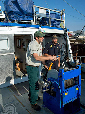 Parks Canada underwater archeologist Ryan Harris, left, and Petty Officer 2nd Class Yves Bernard of the Royal Canadian Navy fit a winch aboard the Martin Bergmann in Cambridge Bay, Nunavut, during final preparations for this year's Franklin search. (Parks Canada)