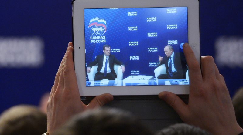 A man takes a photo of Russian President Vladimir Putin, right, and Prime Minister Dmitry Medvedev, with a tablet in 2013. (AP Photo/RIA-Novosti, Alexander Astafyev, Government Press Service)