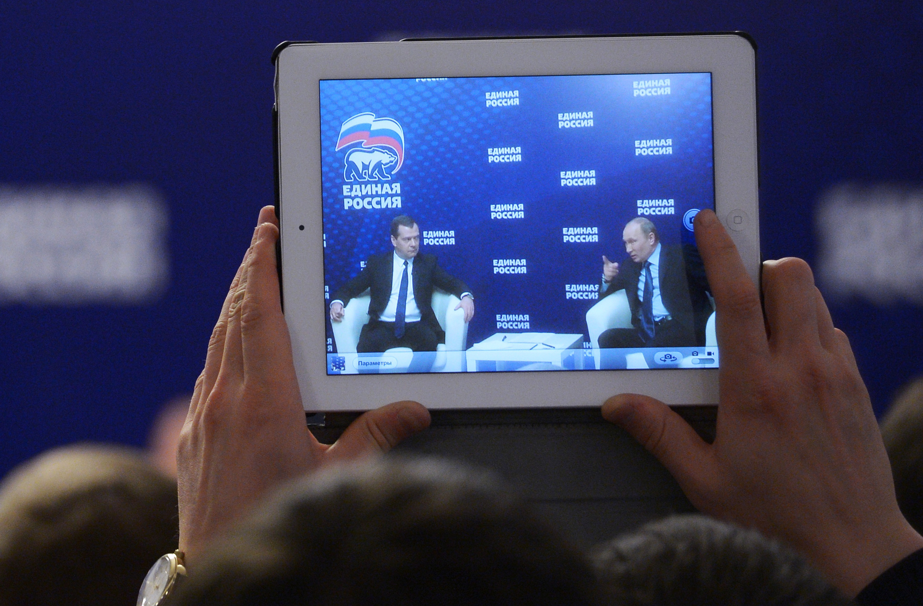 A man takes a photo of Russian President Vladimir Putin, right, and Prime Minister Dmitry Medvedev, with a tablet in 2013. (AP Photo/RIA-Novosti, Alexander Astafyev, Government Press Service)