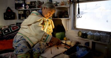 Qapik Attagutsiak of Arctic Bay, Nunavut, lights a qulliq — a traditional oil lamp — in her home. (Courtesy Clare Kines)