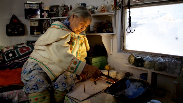 Qapik Attagutsiak of Arctic Bay, Nunavut, lights a qulliq — a traditional oil lamp — in her home. (Courtesy Clare Kines)