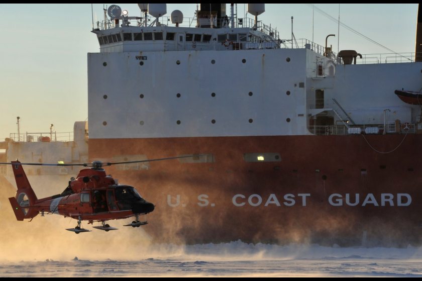 A Coast Guard helicopter crew lands on frozen sea ice in front of the Coast Guard Cutter Healy outside the Port of Nome on Jan. 18, 2012. (U.S. Coast Guard)