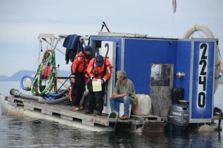 Coast Guard Sector Anchorage enforcement department personnel conduct a boarding aboard a gold dredge vessel near Nome, Alaska, Aug. 3, 2014. Boardings are conducted to ensure that vessel crews are operating safely and complying with environmental regulations. ( Petty Officer 2nd Class Grant DeVuyst / U.S. Coast Guard)
