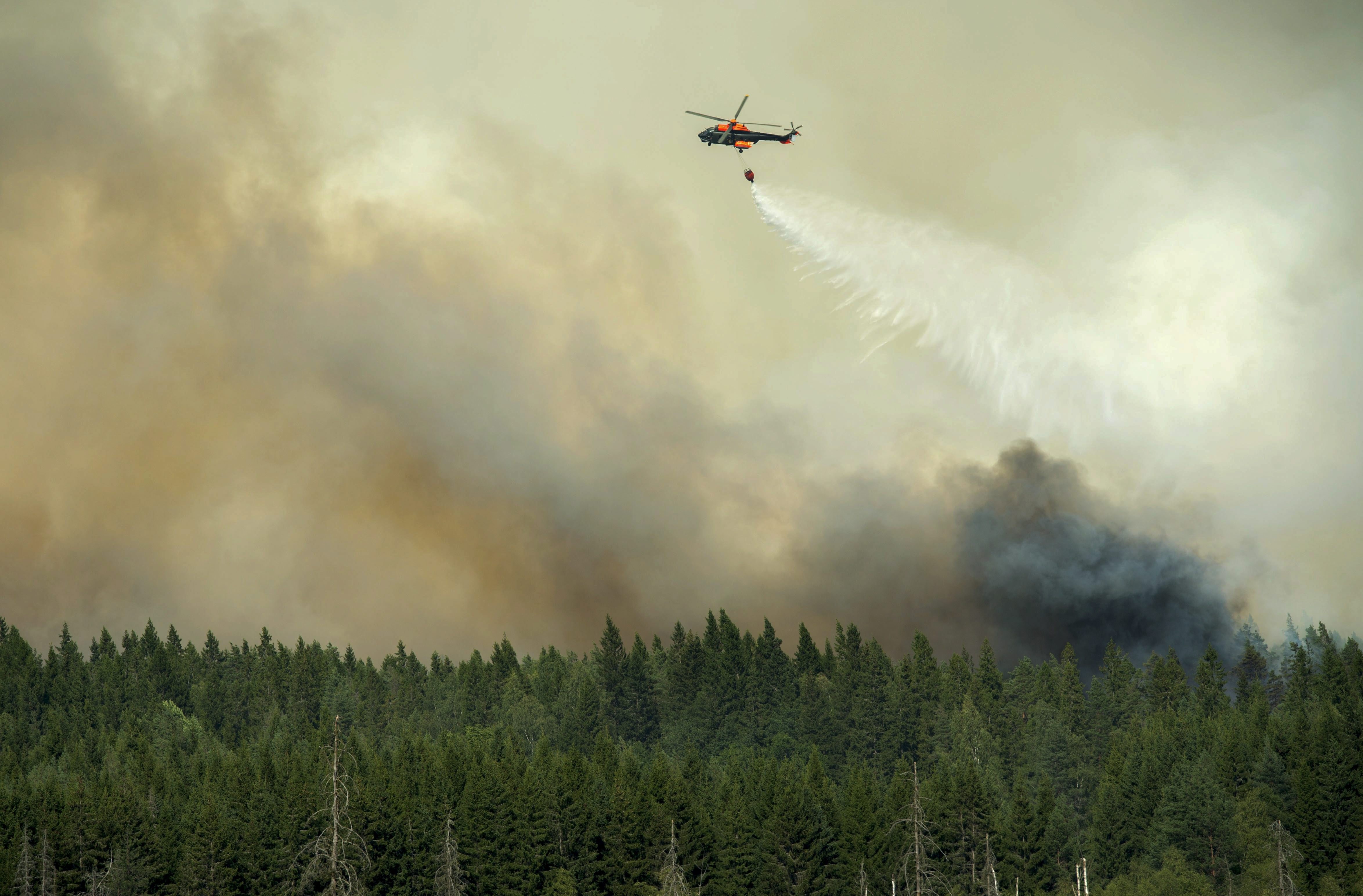 A helicopter drops its load of water on the wildfire front just outside the evacuated village of Gammelby near Sala, Central Sweden, on August 4, 2014. The fire, covering thousands of hectares, is in its fifth day and firefighters believe it will burn for weeks or even months. It is classified as the worst forest fire in Sweden's modern history. (Fredrik Sandberg /AFP/Getty Images)