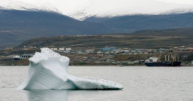 Ice floats past a cargo ship and the hamlet of Pond Inlet in Canada's eastern Arctic in August 24, 2014. (Adrian Wyld / The Canadian Press)