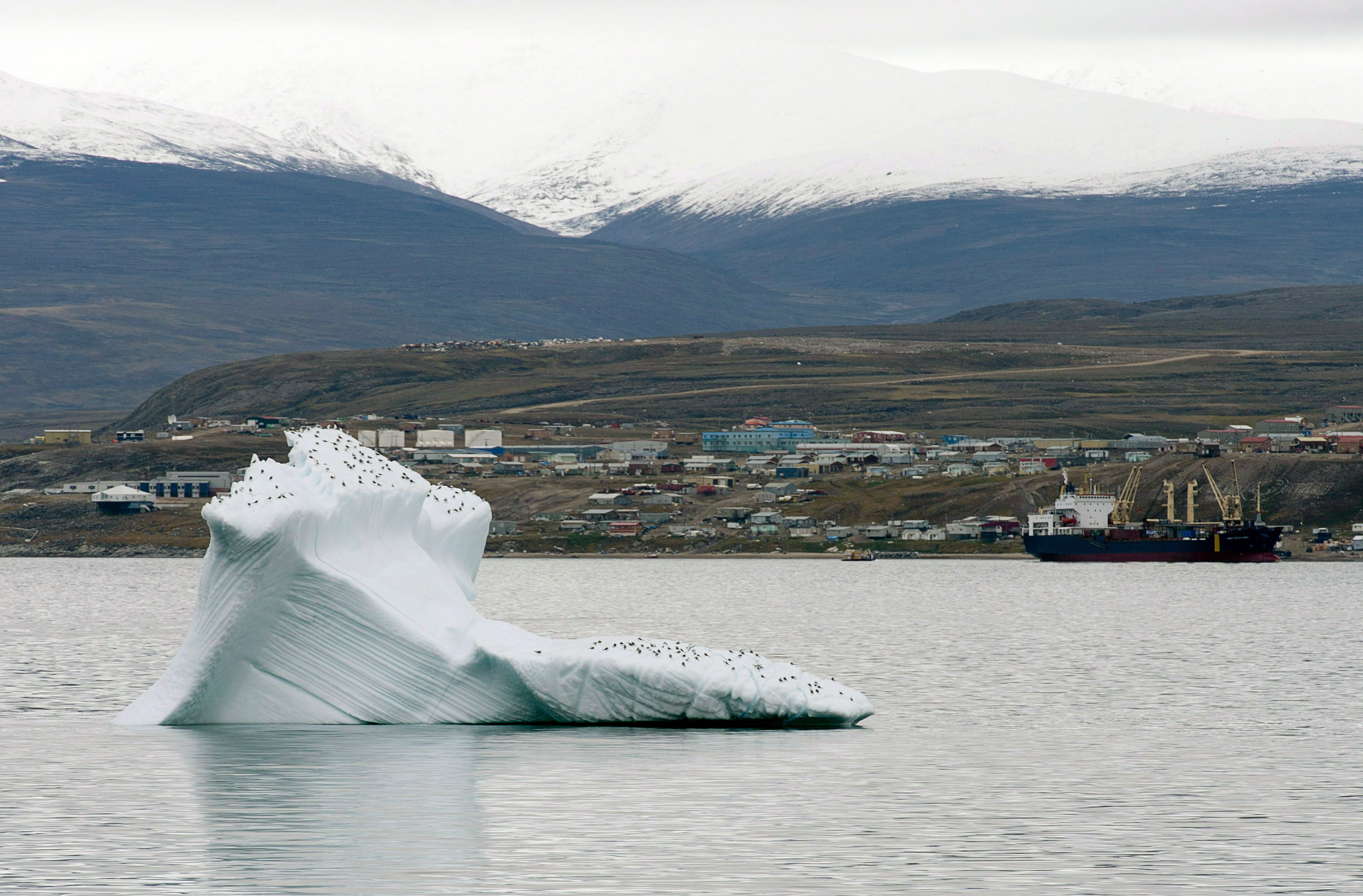 Ice floats past a cargo ship and the hamlet of Pond Inlet in Canada's eastern Arctic in August 24, 2014. (Adrian Wyld / The Canadian Press)