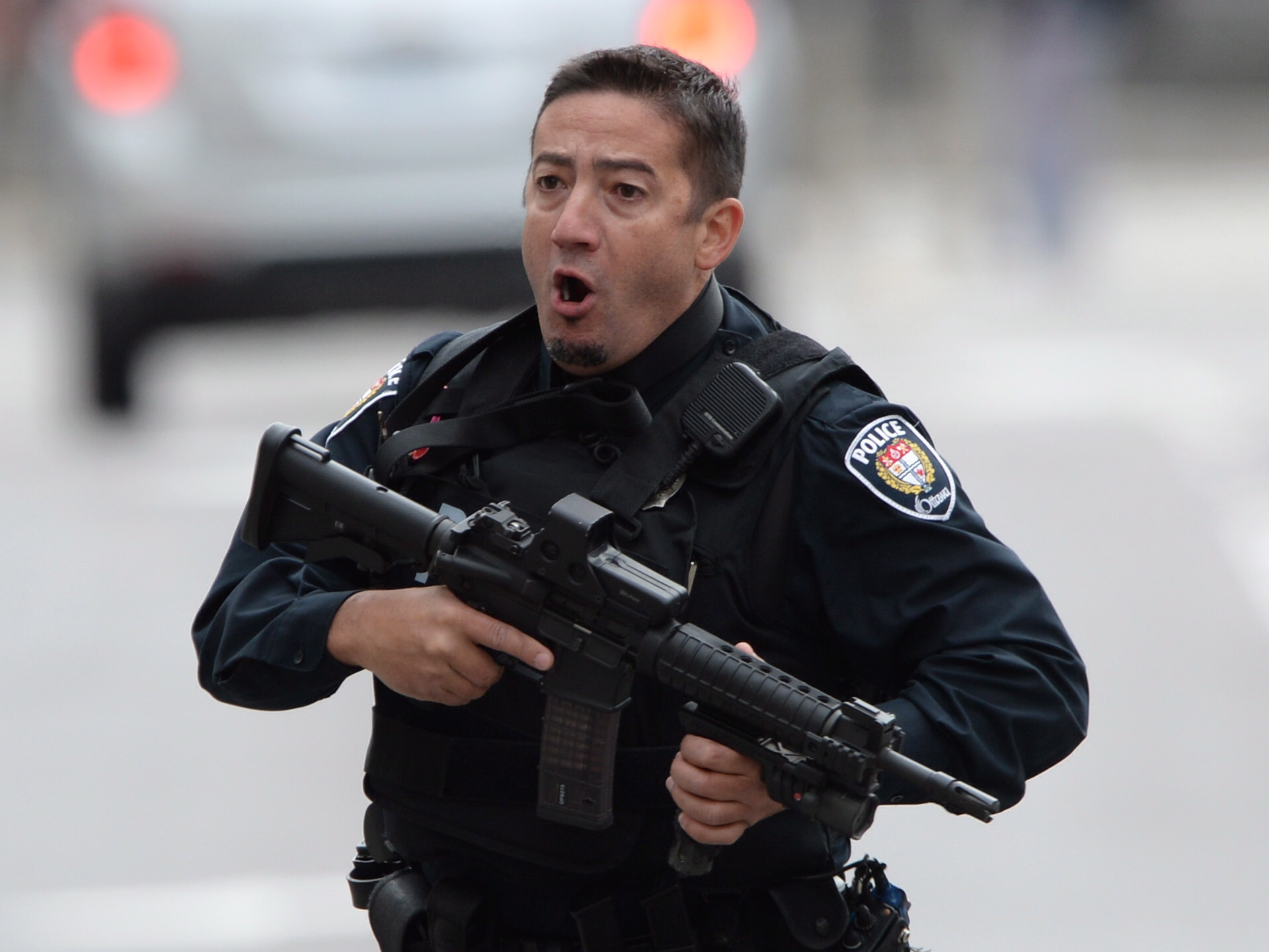 An Ottawa police officer runs with his weapon drawn in Ottawa on Wednesday Oct.22, 2014. (Sean Kilpatrick / The Canadian Press)