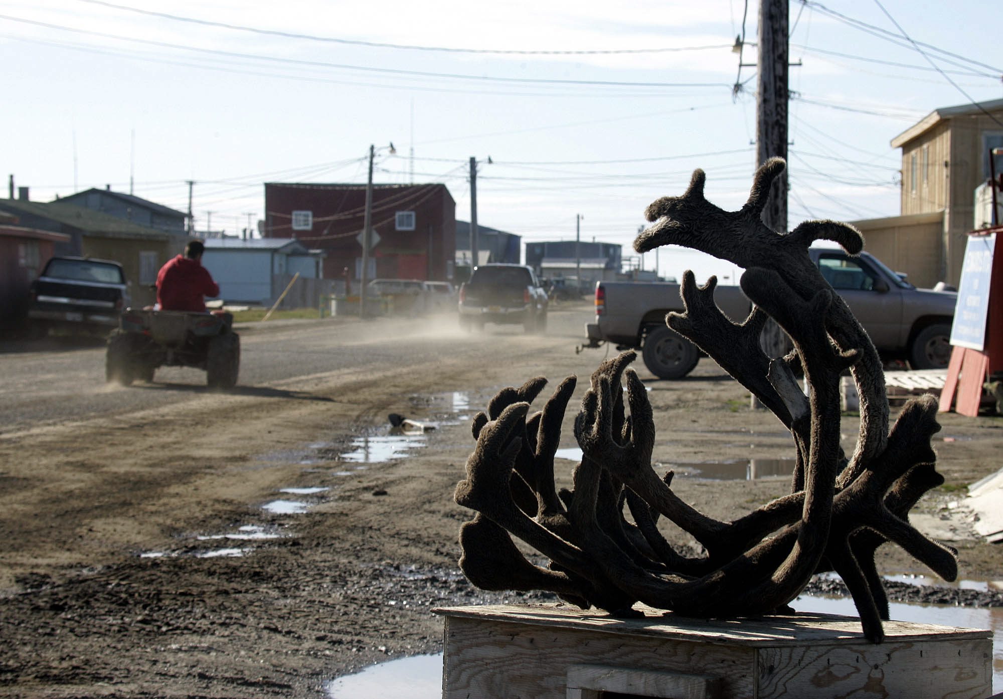 An ATV drives past caribou horns on one of the dirt roads in the Arctic town of Barrow, Alasksa. (Al Grillo / AP)