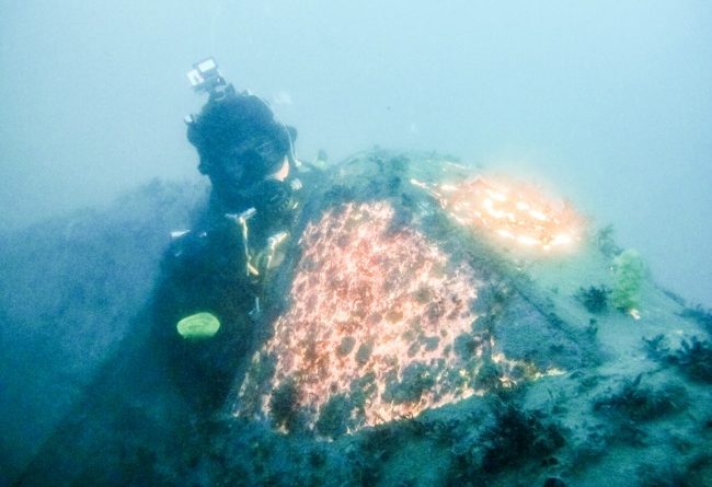 Bjørn Ballo sits in the cockpit of the downed P-40 plane, a vestige of the Second World War under Jarfjord in Kirkenes. (Jimmy Thomson/Barents Observer)