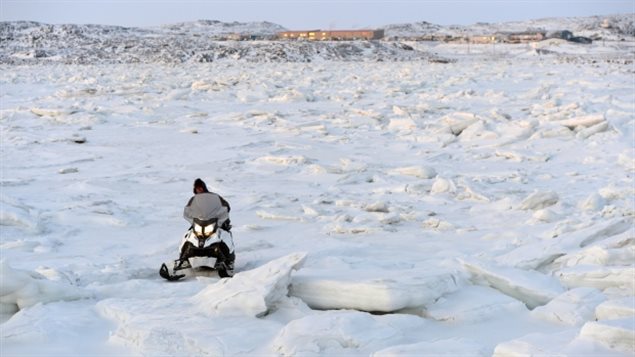 A snowmobiler makes his way through the ice on Frobisher Bay outside of Iqaluit. Canada's Arctic capital of 7,000, like other Arctic communities, is growing rapidly, in part due to migration from smaller communities, according to the second Arctic Human Development Report. (Sean Kilpatrick/Canadian Press)