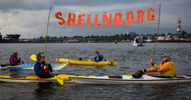 Kayaktivists Jordan Van Voast and Martin Adams hold a sign in protest of the arrival of Shell's Arctic drilling vessel the Noble Discoverer as it came into Everett, Wash. on Tuesday, May 12, 2015. (Daniella Beccaria/seattlepi.com via AP)