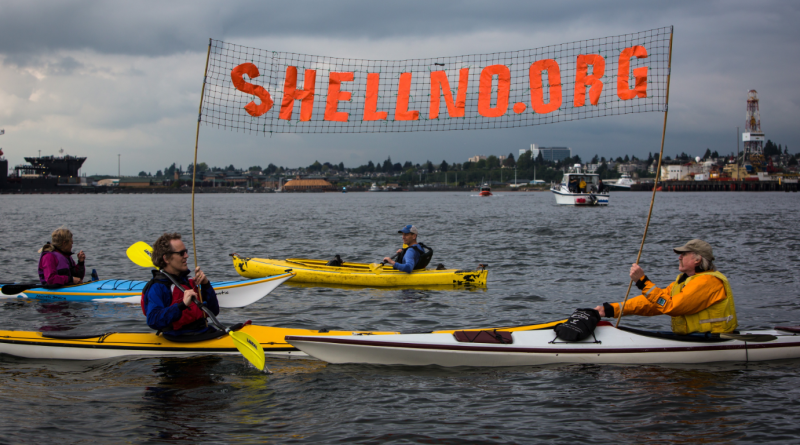 Kayaktivists Jordan Van Voast and Martin Adams hold a sign in protest of the arrival of Shell's Arctic drilling vessel the Noble Discoverer as it came into Everett, Wash. on Tuesday, May 12, 2015. (Daniella Beccaria/seattlepi.com via AP)