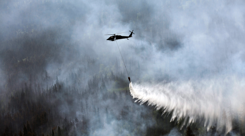 A “Bambi Bucket,” hanging from a helicopter releases hundreds of gallons of water onto the Stetson Creek Fire near Cooper Landing, Alaska on June 17, 2015. (Sgt. Balinda O’Neal/U.S. Army National Guard via AP)