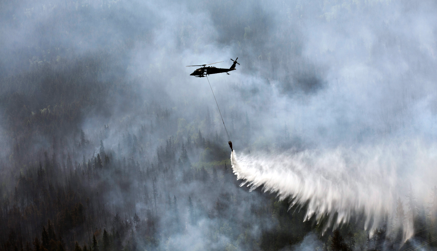 A “Bambi Bucket,” hanging from a helicopter releases hundreds of gallons of water onto the Stetson Creek Fire near Cooper Landing, Alaska on June 17, 2015. (Sgt. Balinda O’Neal/U.S. Army National Guard via AP)