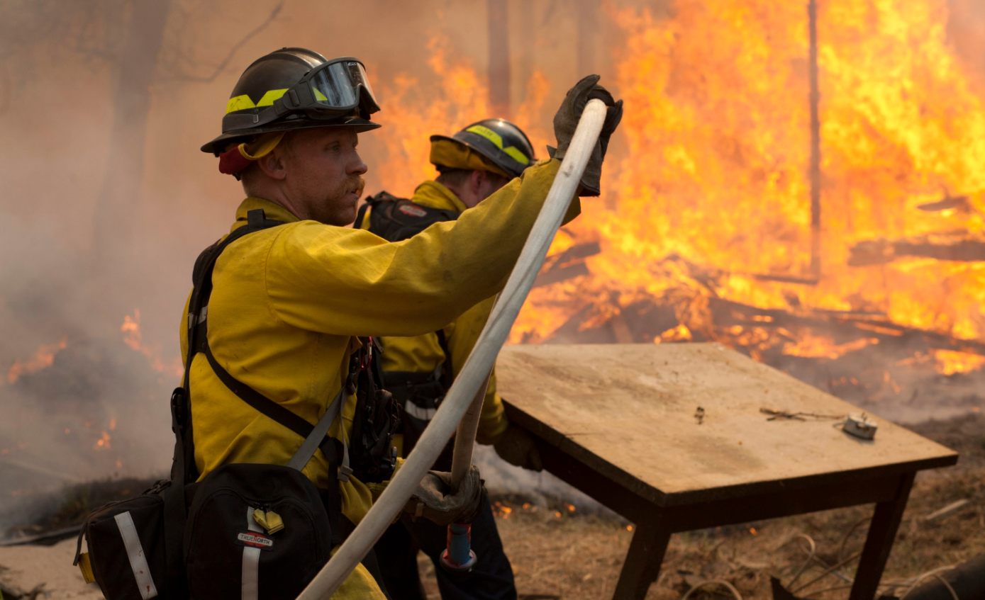 In this May 25, 2014 file photo, Central Emergency Services firefighter Dan Jensen maneuvers a hose into position to fight a portion of a wildfire in the Funny River community of Soldotna, Alaska. Wildfires are blistering Alaska forests with increasing frequency and intensity and forest managers and climate scientists are trying to explain why and predict what's next. One common factor associated with the increase, which doesn't bode well for 2015 or beyond, is warm weather, even if experts don't explicitly blame climate change. (Rashah McChesney/Peninsula Clarion via AP)