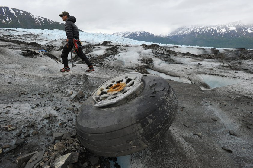 U.S. Marines Capt. David Gooch, with the Defense POW/MIA Accounting Agency, walks past an aircraft wheel assembly resting on the ice surface of Colony Glacier in Alaska on Wednesday, June 10, 2015. For the fourth consecutive summer, a team of military members and scientists are combing the surface of Colony Glacier looking for remains and personal effects that can be used to identify the 52 people who perished when a U.S. Air Force Douglas C-124 Globemaster II crashed into Mount Gannett, about 15 miles away, while flying in severe weather in 1952. (Bill Roth/Alaska Dispatch News)