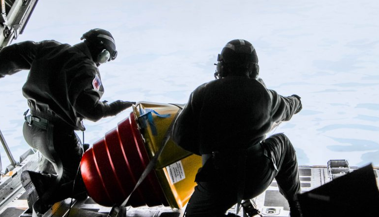 Two U.S. Coast Guard drop masters on an Arctic Domain Awareness flight push a weather buoy into the ocean north of Deadhorse on Tuesday, July 14, 2015. (Kamala Kelkar/Alaska Dispatch News)