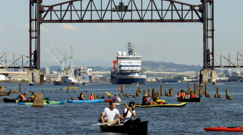 oaters gather as the Royal Dutch Shell PLC icebreaker Fennica heads under a railroad bridge and up the Willamette River in Portland, Ore., Thursday, July 30, 2015. The Fennica left dry dock and made its way down the Willamette River toward the Pacific Ocean soon after authorities forced the demonstrators from the river and the St. Johns Bridge. (Don Ryan/AP)