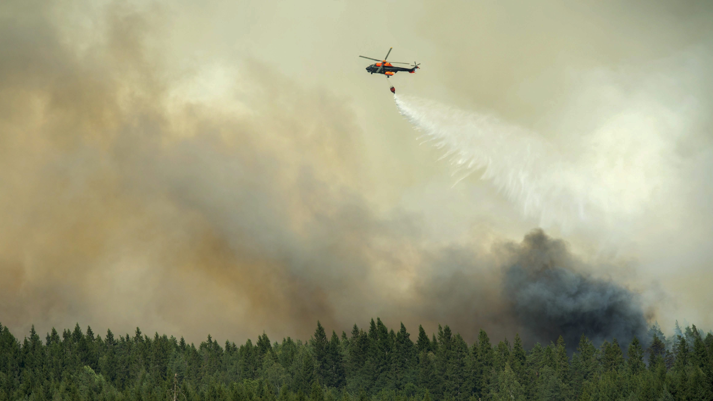 A helicopter drops a load of water on the wildfire front just outside the evacuated village of Gammelby near Sala, Central Sweden, on August 4, 2014. The fire was classified as the worst forest fire in Sweden's modern history. (Fredrick Sandberg/AFP/Getty Images)