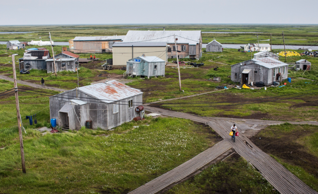 People walk down the elevated, raised wooden sidewalks - created so people don't sink into the melting permafrost - on July 5, 2015 in Newtok, Alaska. The community's generator broke this week forcing residents to burn wood and cardboard to heat their homes. (Andrew Burton/Getty Images)