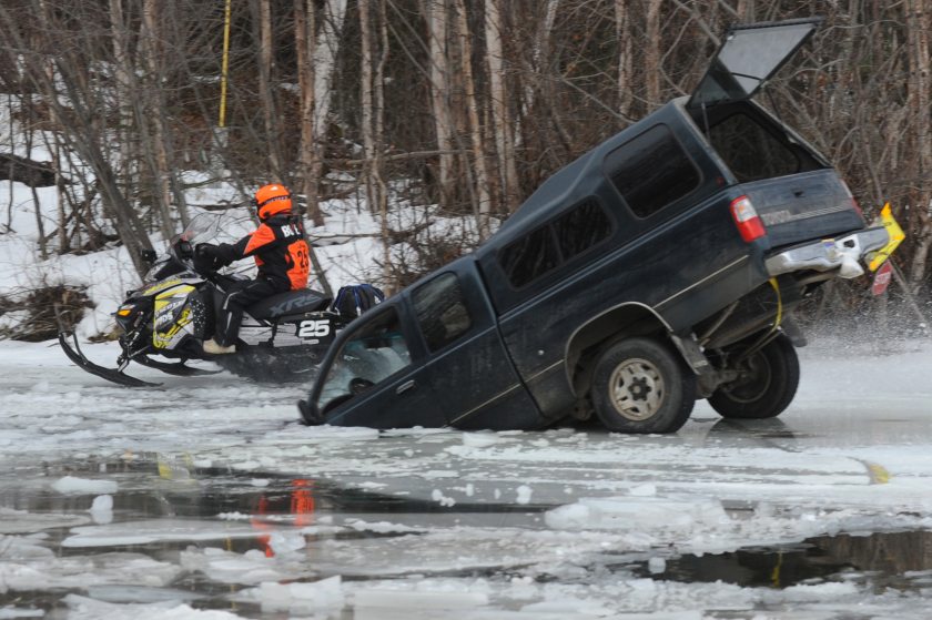 Rookie Tyler Bogert of Big Lake zips past a pick-up truck that broke through the ice on a canal leading to Flat Lake as forty-one two-person teams left the Iron Dog restart on Big Lake on Sunday, Feb. 21, 2016, during the 2,000 mile (3,218 km) race through the Alaska wilderness to Nome with a Fairbanks finish. Photo: Bill Roth/ADN