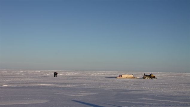 An Inuit hunter stands watch over a seal breathing hole in the sea ice. (Levon Sevunts/Radio Canada International)