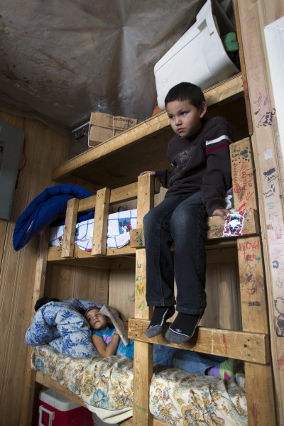 Seven-year-old Ferlin Lahtal (right) and his sister, five-year-old Verna sit in their home-made bunk beds in thier home in Attawapiskat, Ontario Saturday December 17, 2011. Twenty-one people live in the house that has plastic on the ceilings to stop water entry. FRANK GUNN/THE CANADIAN PRESS