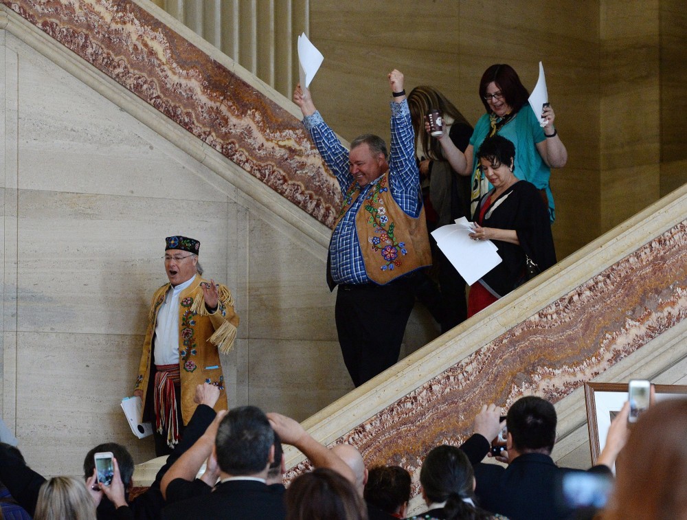 Metis National Council President Clement Chartier, left, and David Chartrand, president of the Manitoba Metis Federation, centre, celebrate following the decision at the Supreme Court of Canada in Ottawa on Thursday, April 14, 2016. Sean Kilpatrick/THE CANADIAN PRESS