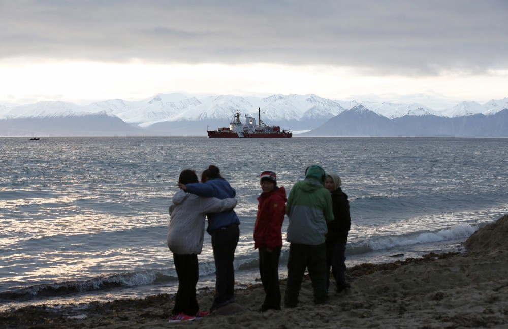 Local children stand on the shore as the Coast Guard ship Des Groseilliers sits in the waters near the Arctic community of Pond Inlet, Nunavut August 23, 2014. Chris Wattie/REUTERS