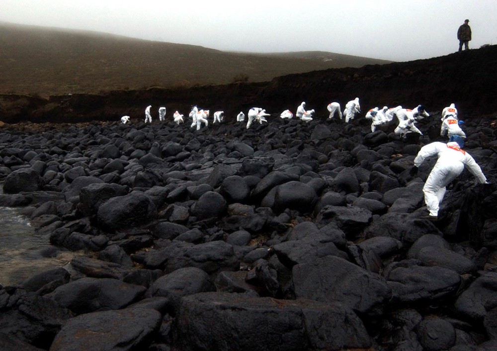 A group of soldiers form a line to clean up fuel oil spilled from the "Prestige" oil tanker near the coastal town of Muxia on Spain's devastated North West Atlantic coast on January 27, 2003. The aging, single-hulled tanker foundered off the coast of Galicia in November 2002 with 77,000 tonnes of heavy fuel oil on board, causing Spain's worst ever ecological disaster, contaminating hundreds of miles of coast and putting thousands of fishermen out of work. REUTERS