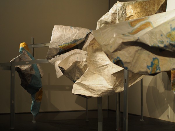 “Subsistence,” a sculpture by Marek Ranis from old military maps suspended on metal fish racks, part of the Anchorage Museum’s “The View From Up Here” exhibit. (Zachariah Hughes/ Alaska Public Media)