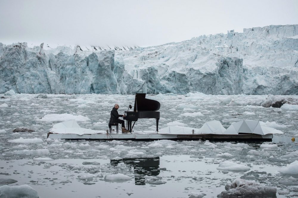 In this undated photo provided by Greenpeace Spain, Italian composer and pianist Ludovico Einaudi performs one of his own compositions on a floating platform in the Arctic Ocean, in front of the Wahlenbergbreen glacier, in Svalbard, Norway. (Pedro Armestre/Greenpeace Spain via AP)