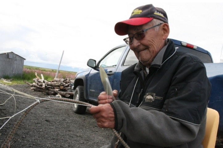 Quinhagak fisherman Jimmy Anaver on Friday, July 22, 2016, shows how he hangs floats onto his net. (Lisa Demer / Alaska Dispatch News)