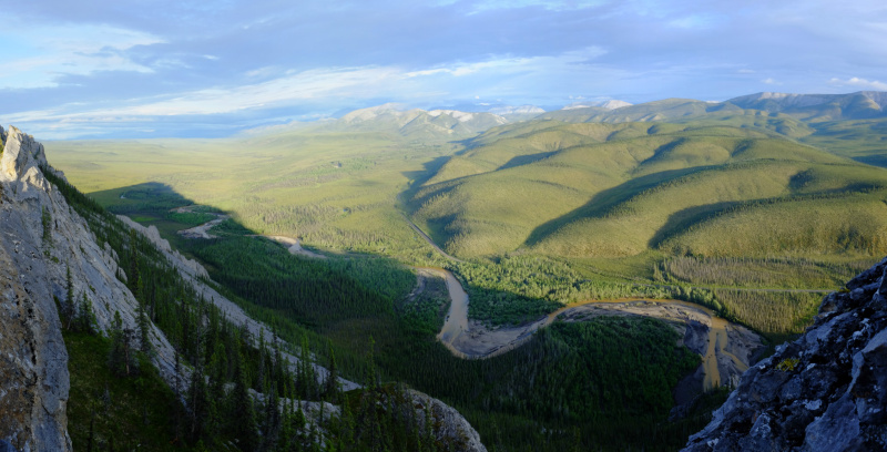 The Dempster Highway curving along the side of the hills, with the muddy Engineer Creek flowing in the foreground. (Mia Bennett)