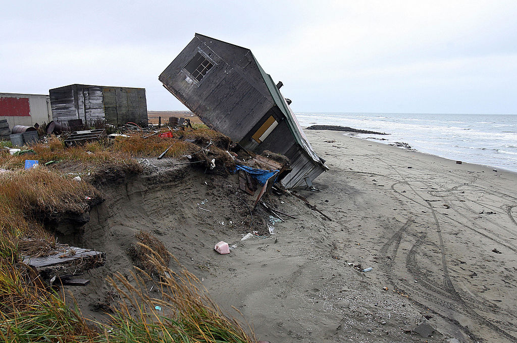 A home destroyed by beach erosion tips over 27 September 2006 in the the Alaskan village of Shishmaref. Temperatures that have risen 15F (4.4C) over the last 30 years are causing a reduction in sea ice, thawing of permafrost along the coast, making the shoreline vulnerable to erosion. (GABRIEL BOUYS/AFP/Getty Images)