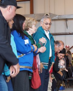 Around 200 people attended the dedication ceremony, including Willie Hensley, pictured here in the green atikłuk. (Zachariah Hughes/ Alaska Public Media – Kotzebue)