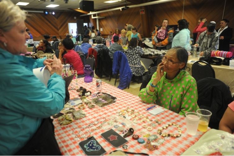 Crystal Serenity cruise ship passenger Lana Breakie, from San Antonio, TX, looks at the ivory offered for sale by Elsie Weyanna, from Shishmaref, AK in Nome, AK on Sunday, August 21, 2016. The cruise ship is on its way across the Northwest Passage, the largest passenger ship to attempt the crossing. (Bob Hallinen / Alaska Dispatch News)