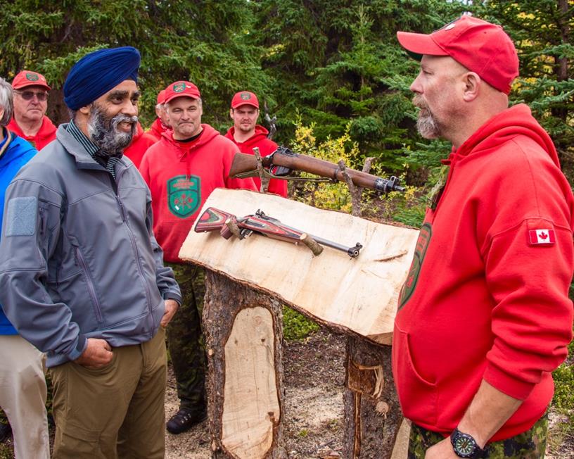 Member of the Canadian Rangers explains the differences between the current Lee Enfield model (top) and the new rifle (bottom) to Minister Sajjan (L) during his visit to Operation NANOOK. (Canadian Armed Forces)