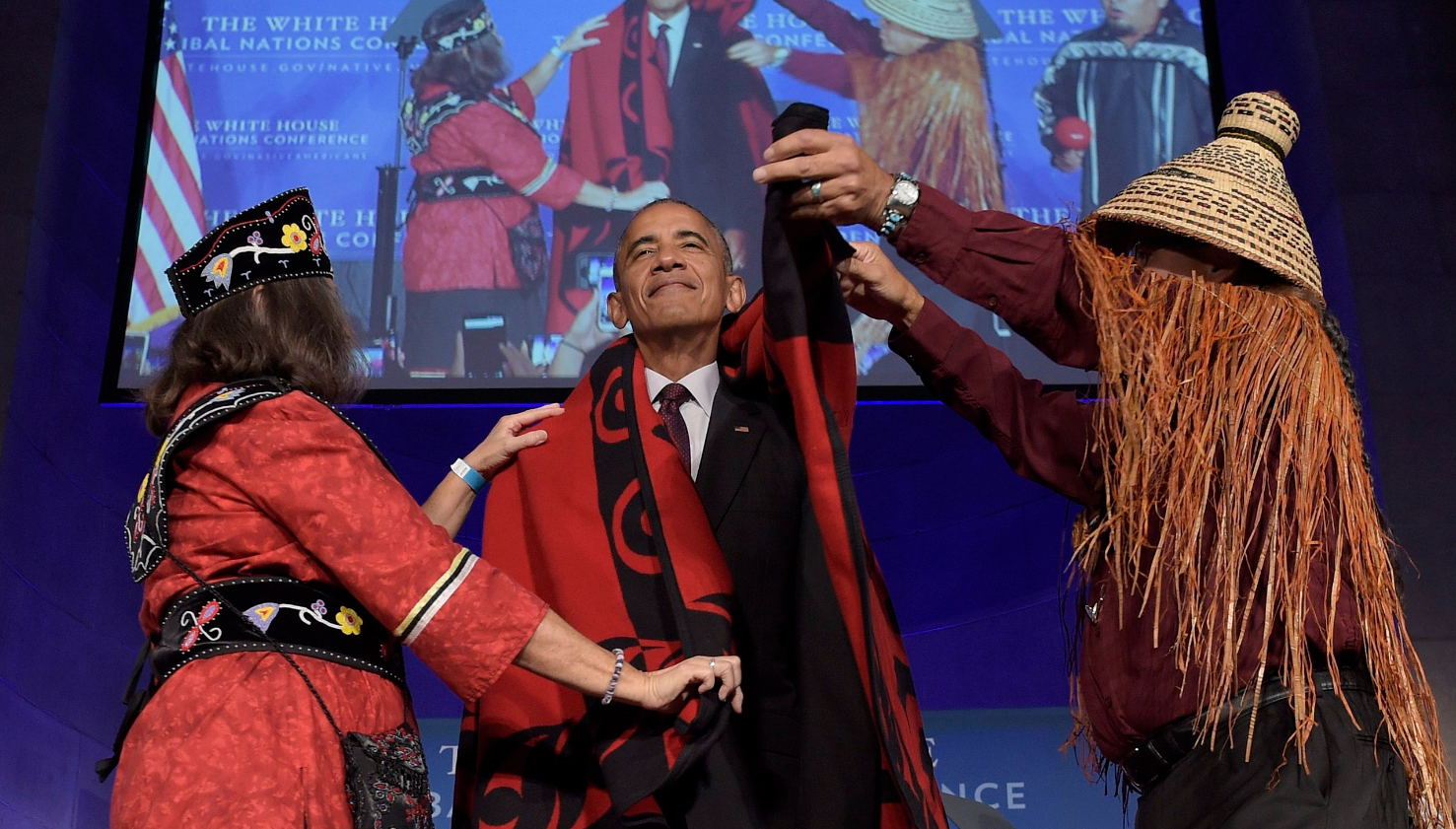 Mohegan Chief Lynn Malerba, left, and Brian Cladoosby, right, President of National Congress of American Indians, cover President Barack Obama with a blanket at the 2016 White House Tribal Nations Conference, Monday, Sept. 26, 2016, at the Mellon Auditorium in Washington. (Susan Walsh/AP/The Canadian Press)