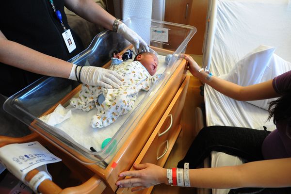 Newborn Ashton Sergie is tended to by nurse practitioner Laurie Soule, left, and mom Sophianne Sergie on Thursday in Family Birthing Services at the Alaska Native Medical Center. Ashton was set to have a blood sample taken later in the day for screening for CPT1A Arctic variant and other conditions. (Erik Hill / Alaska Dispatch News)