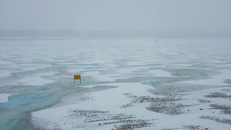 The frozen Amur river separating Russia and China between the cities of Blagoveshchensk and Heihe. The yellow sign in the frozen river warns onlookers not to cross. (Mia Bennett)