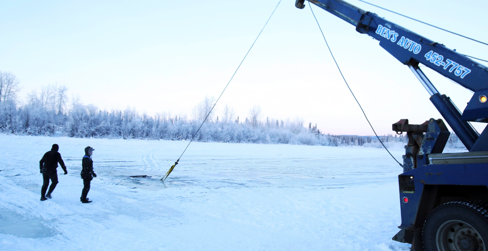 In this Dec. 19, 2014 photo, a dive crew watches the recovery of a vehicle from the icy water near the Pike's Landing Chena River Ice Bridge entrance in Fairbanks, Alaska. At least two vehicles recently sank into the Chena River on a section long used as an ice-covered shortcut between Airport Way and Chena Small Tracts Road. (Eric Engman/The Fairbanks Daily News-Miner/AP)