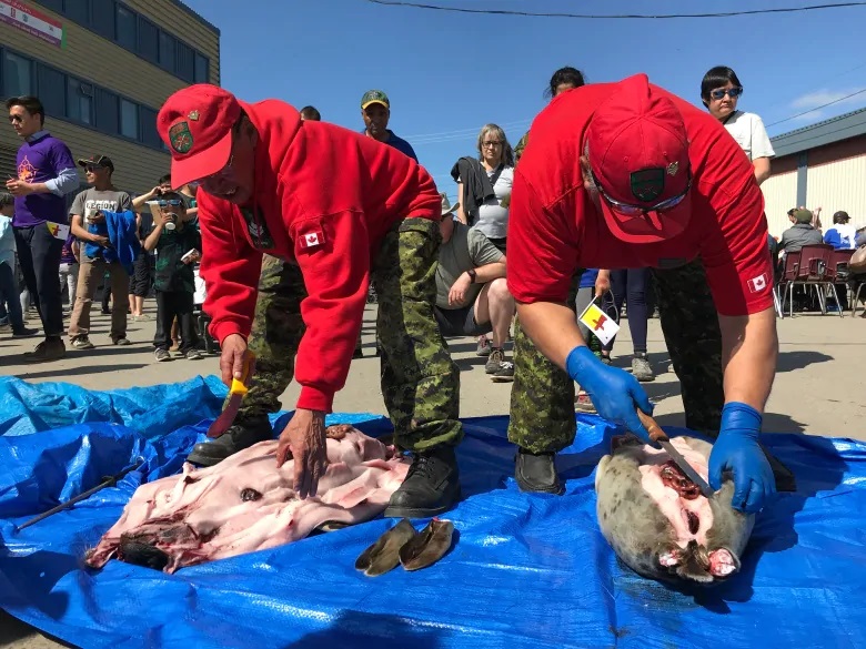 Canadian Rangers prepare seals and hand out fresh meat as part of the day’s celebratory feasting. (Sara Frizzell/CBC)